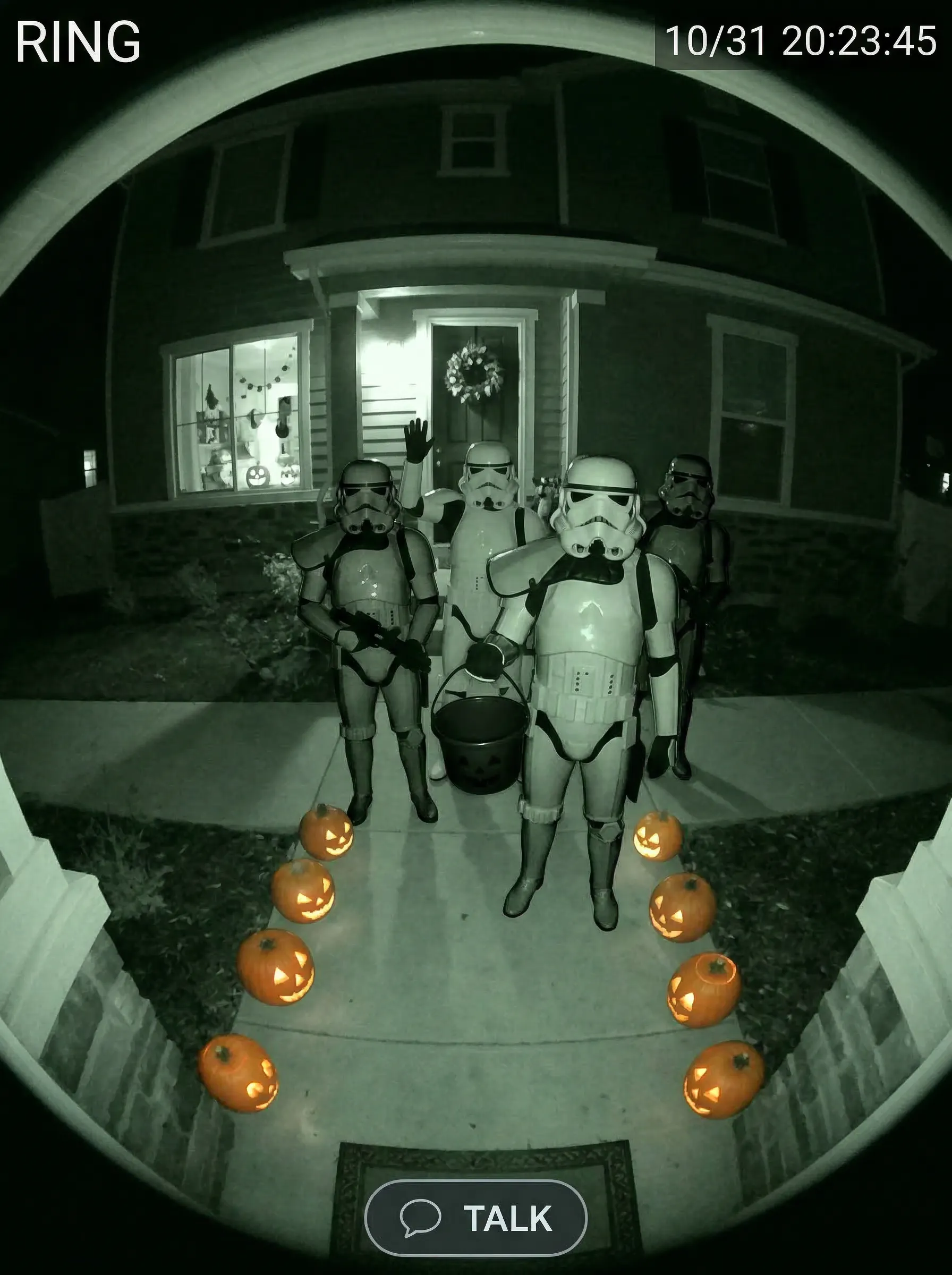 Ring doorbell camera footage of a squad of stormtroopers politely asking for candy on Halloween night, grainy night vision look.